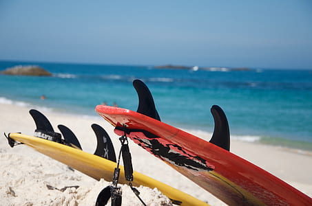 Yellow And Red Surfboards Near Blue Calm Body Of Water thumbnail