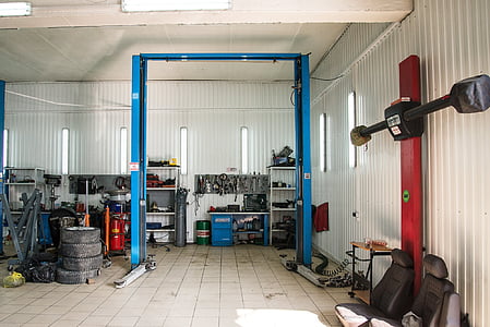 empty blue engine hoist inside white room surrounded by assorted vehicle tools thumbnail
