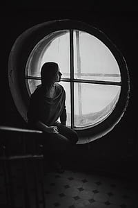 grayscale photography of woman sitting on window thumbnail