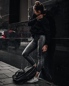 woman leaning on black wall while raising her right leg thumbnail