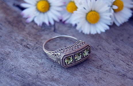 gold-colored ring near white daisy flowers on brown surface thumbnail