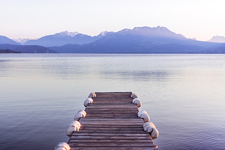 brown wooden dock and body of water near mountains under clear blue sky photo taken during daytime thumbnail