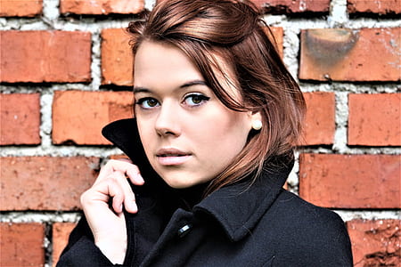 closeup photo of woman wearing black coat near brick wall thumbnail