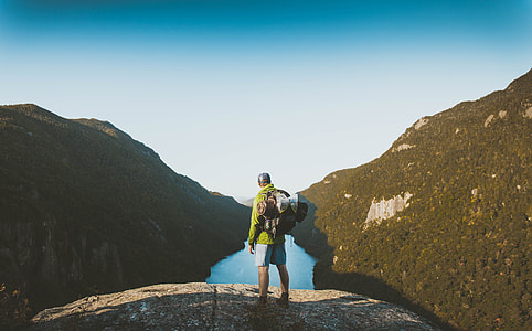 man standing on the edge of rock overlooking river thumbnail