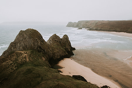 rock formation beside body of water during daytime thumbnail