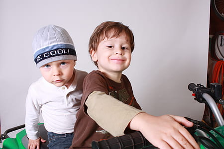 two boy's riding green plastic ATV inside room thumbnail
