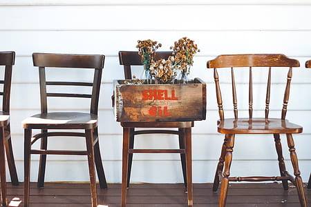 withered chrysanthemum flowers in brown wooden crate on brown wooden chair beside two brown wooden Windsor chairs thumbnail