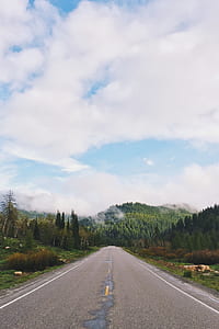 road towards green hill under white clouds thumbnail