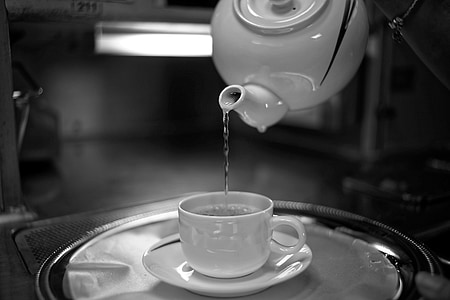 selective focus photography of water poured by pitcher unto white ceramic teacup with saucer on tray thumbnail
