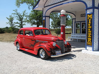 classic red hardtop coupe fueling at classic red gas pump during daytime thumbnail