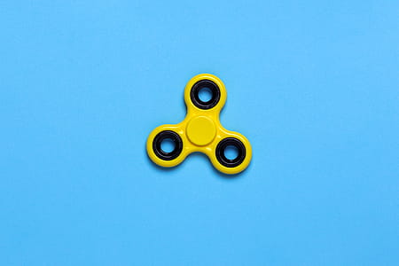 Yellow Tri-spinner Fidget Toy on Blue Tabletop thumbnail