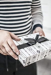 person holding white and black gift box thumbnail