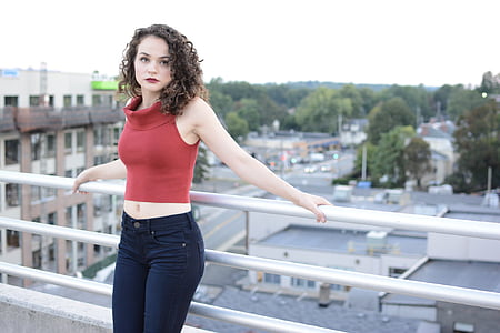 woman in red crop top leaning on silver fence thumbnail