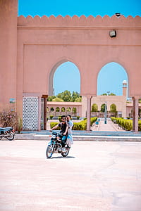 Two Man Riding Motorcycle Near Concrete Building thumbnail