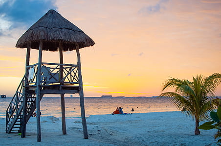 two persons sitting on beach during sunset thumbnail