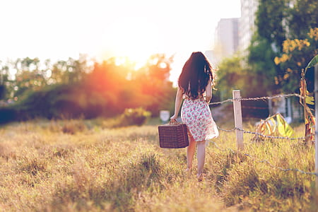 Woman in Brown Floral Dress Walking Near Fence thumbnail