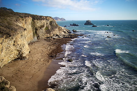 seashore near brown rocky mountain thumbnail