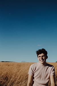 smiling man standing on a brown field under blue skies thumbnail
