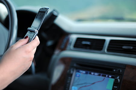 person holding black flip phone sitting inside vehicle thumbnail