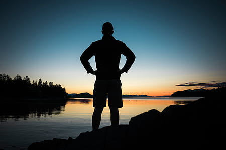 silhouette of a man standing near water thumbnail