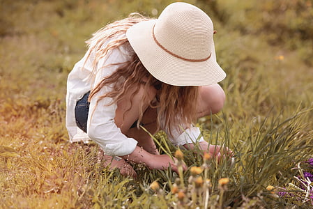 woman with sunhat picking flowers on field thumbnail