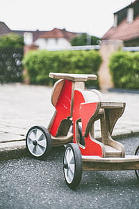 phoot of red and brown wooden ride-on toy on gray surface thumbnail