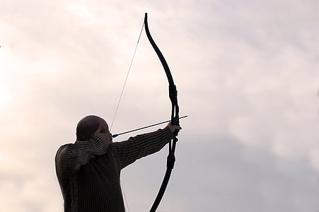 person wearing black long-sleeve top holding long bow thumbnail