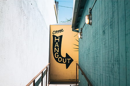 photo of beige and black Com hangout signage near teal wall thumbnail
