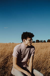 man wearing gray turtleneck top sitting in the grass field thumbnail