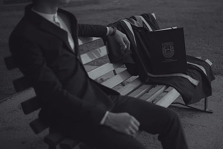 grayscale photo of man sitting at bench thumbnail