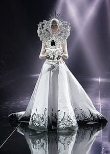 woman wearing white gown holding silver-colored crown thumbnail