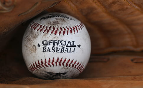white and red baseball ball in brown mitt thumbnail