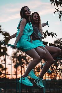 Two Girls Sitting on Gray Metal Rail thumbnail