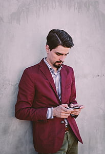 man leaning on wall holding phone thumbnail