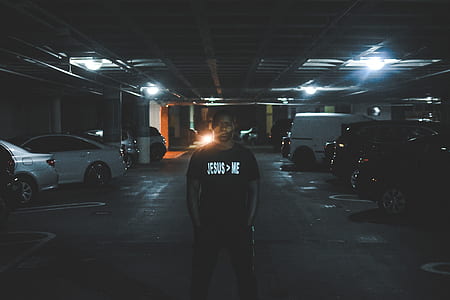 man in black shirt standing on vehicle parking area on focus photo thumbnail