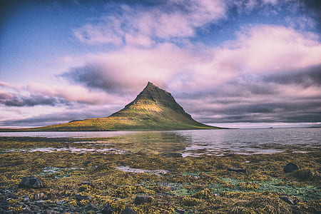 body of water near mountain during daytime thumbnail