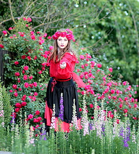 woman in red and black dress standing beside flowers thumbnail