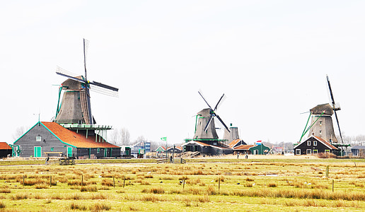 three gray windmills on green grass field during daytime thumbnail