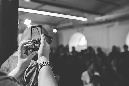 grayscale photo of person taking photo of crowd thumbnail