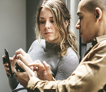 man and woman looking at smartphone inside room thumbnail