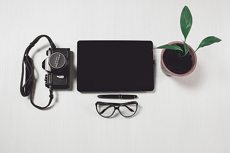 black tablet computer near camera, potted plant, twist pen, and black-framed eyeglasses thumbnail