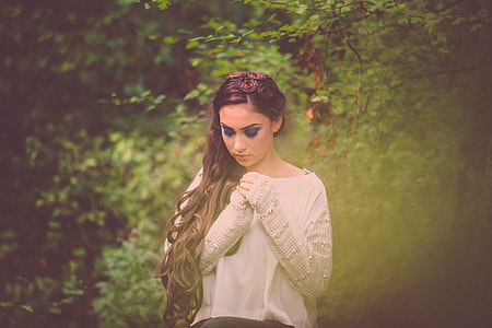 woman wearing white long sleeve top looking down and holding hand together thumbnail