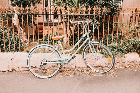 white cruiser bike parks beside brown metal fence thumbnail