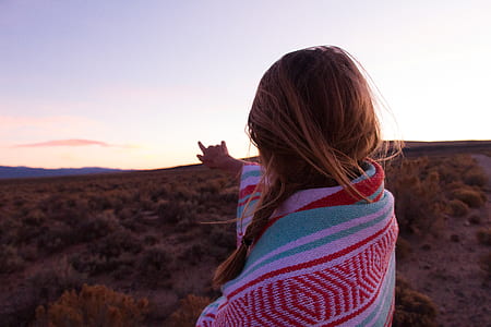 woman covered in blanket pointing her hand on mountain thumbnail