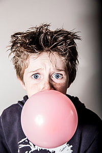 man blowing pink balloon and taking close-up selfie thumbnail
