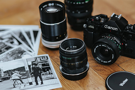 Old Zenit camera and a Canon camera with black-and-white photos on a wooden table thumbnail