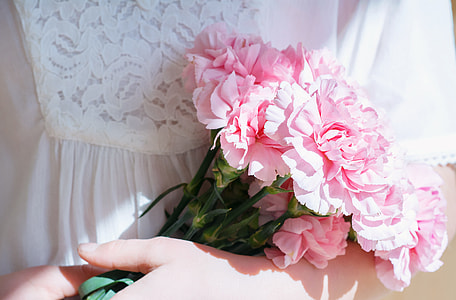 person in white dress carrying pink Carnation flowers bouquet thumbnail