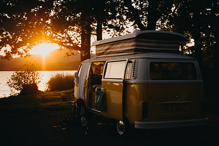 yellow and white van under tree shade near body of water thumbnail
