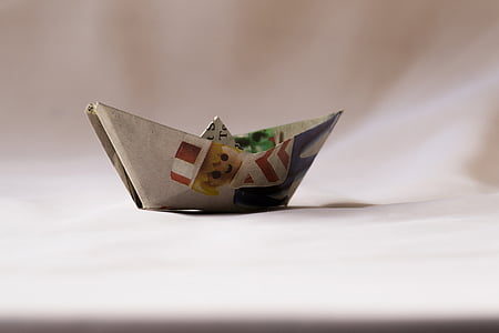 white, red, and black paper boat on white textile thumbnail