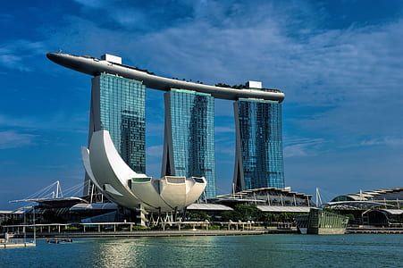 three tall blue buildings near sea during daytime thumbnail